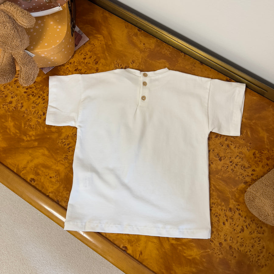 T-shirt basica color latte in jersey di cotone elasticizzato con taschino e bottoni sul retro