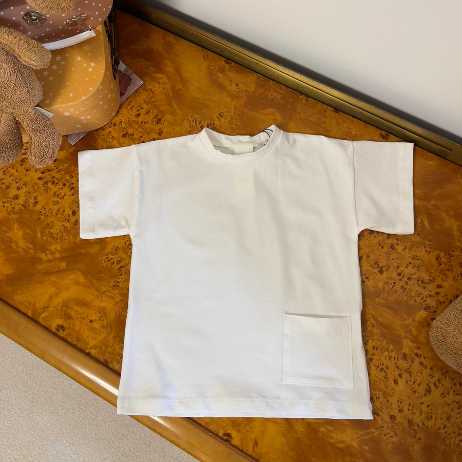 T-shirt basica color latte in jersey di cotone elasticizzato con taschino e bottoni sul retro